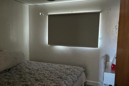 Sleek custom roller shades fitted over a large bedroom window with soft daylight filtering through.